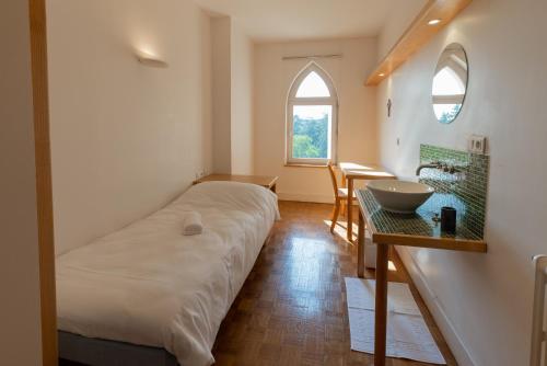 1 dormitorio con 1 cama, lavamanos y mesa en Hôtellerie de l'Abbaye, en Bellegarde