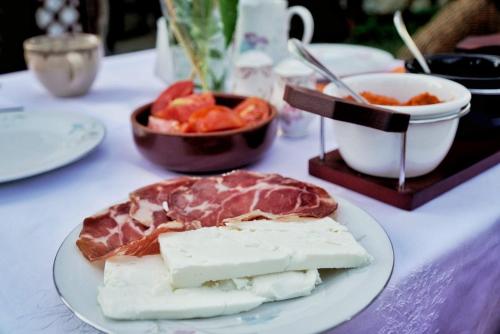a plate of food with meats and cheese on a table at Cottage Modrich in Struga