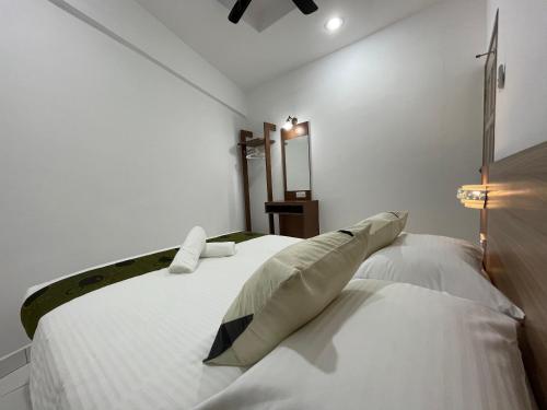 a white bedroom with a large white bed with pillows at Century Suria Aparment Langkawi by Zervin in Kuah