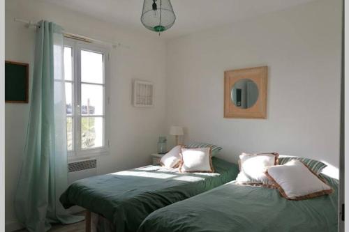 deux lits assis dans une pièce avec une fenêtre dans l'établissement Jolie maison de vacances Noirmoutrine, à Noirmoutier-en-l'lle