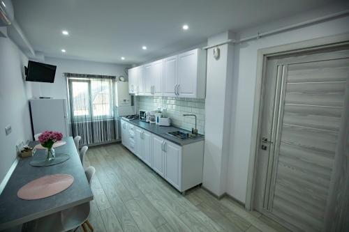 a kitchen with white cabinets and a table and a door at Apartament Serban in Tîrgu Ocna