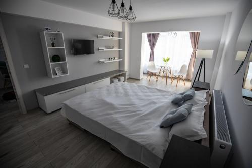 a white bedroom with a large bed in a room at Apartament Serban in Tîrgu Ocna