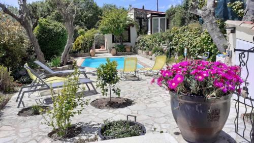 a patio with a pool and some chairs and flowers at Le Jardin du Cannet in Bagnols-en-Forêt