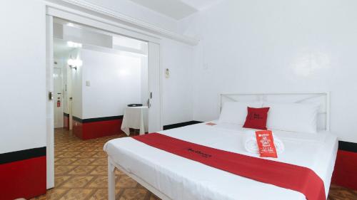 a bedroom with a white bed with a red pillow on it at RedDoorz at The Providence Tower in Manila