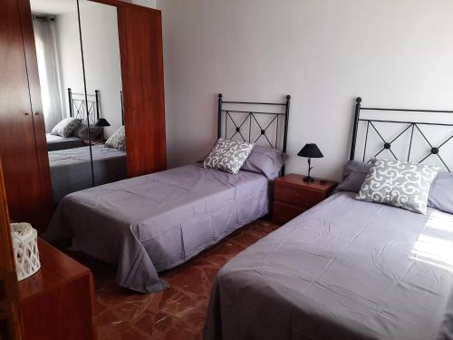 a bedroom with two beds and a mirror at Casa de la Gloria in Baños de la Encina