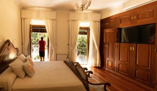um quarto com uma cama e uma televisão e uma pessoa na janela em Alojamiento Turístico Fuente del Rey em Priego de Córdoba