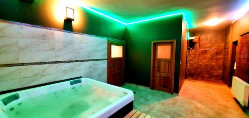 een grote badkamer met een bad met groene verlichting bij Hotel Farma Vysoká in Chrastava
