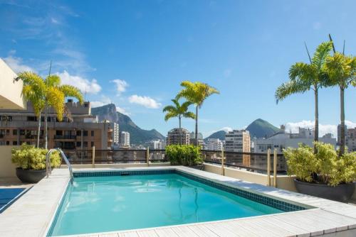 una piscina en la azotea de un edificio con palmeras en Leblon Inn, bonito apartamento en Río de Janeiro