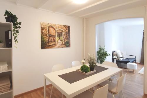 uma sala de jantar branca com uma mesa e cadeiras brancas em Bright and modern apartment in the heart of Altstätten em Altstätten