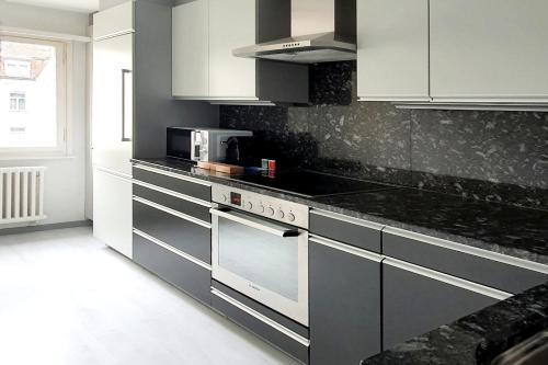 uma cozinha com bancadas pretas e armários brancos em Bright and modern apartment in the heart of Altstätten em Altstätten