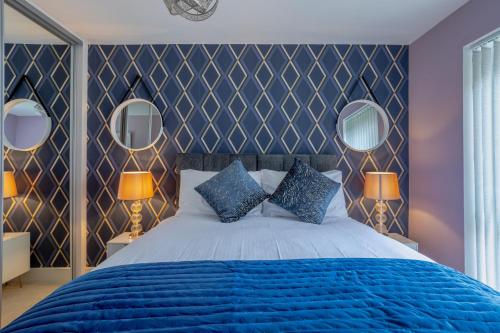 a bedroom with a blue bed and two mirrors at LillyRose Apartments - Hemel Hempstead, Free Parking, Free Wi-Fi in Kings Langley