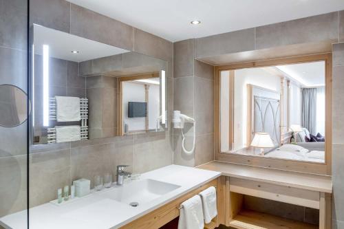 La salle de bains est pourvue d'un lavabo et d'un grand miroir. dans l'établissement Hotel Bellevue - 4 Sterne superior, à Obergurgl