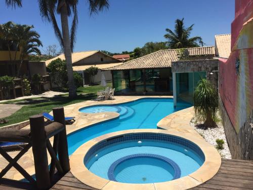 una piscina con terraza de madera junto a una casa en Pousada Coração de Búzios en Búzios