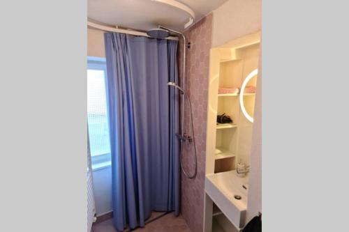 a bathroom with a shower curtain and a sink at Petit bijou de Sainte-Croix in Sainte-Croix