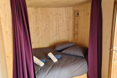 Petit bijou de Sainte-Croix في سانت-كروا: سرير في غرفة مع وسادتين وستارة