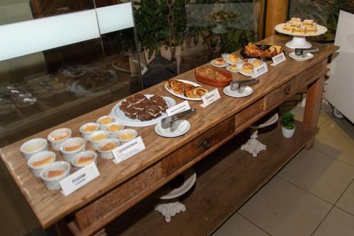 a table with various pastries and desserts on it at Limeira Suítes in Limeira