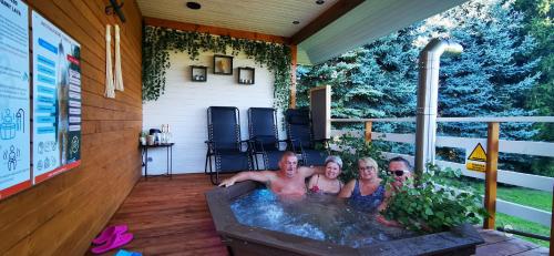 a group of people in a hot tub on a patio at Sielanówek - Orzechowa Chatka z sauną wanną termalną jacuzzi in Żywiec