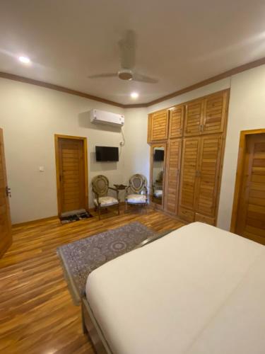 a bedroom with a white bed and wooden floors at ISLE OF HIGHLAND TOURS Guest House in Gilgit