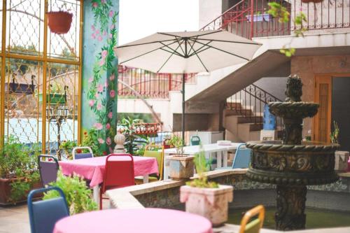 eine Terrasse mit Tischen, Stühlen und einem Sonnenschirm in der Unterkunft Damask Rose, Lebanese Guest House in Jounieh