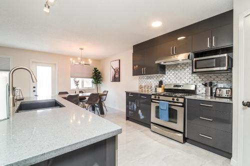 a kitchen with stainless steel appliances and a dining room at Spa Oasis Home - Hot Tub - King Bed - BBQ - Garage - Pets! in Edmonton