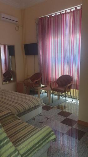 a hotel room with two beds and chairs and a window at Vila club 011 in Dedinje
