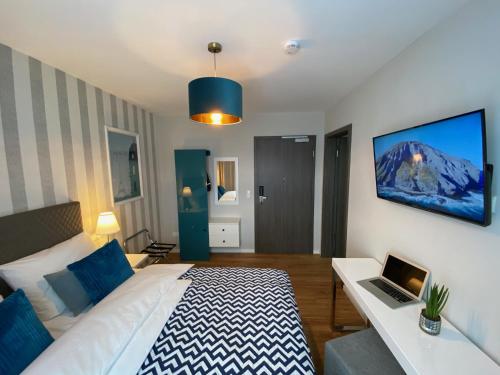 a bedroom with a bed and a laptop on a table at Hotel Tortuga & Tex-Mex Bar & Grill in Gravenwerth