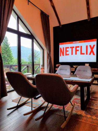 einen Tisch mit Stühlen und ein Netflix-Schild an der Wand in der Unterkunft Casa Larisa Apartments in Sinaia
