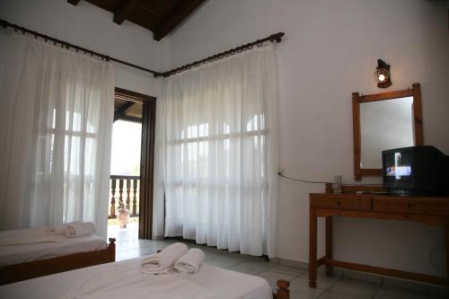 - une chambre avec 2 lits, un miroir et une télévision dans l'établissement Villa Frideriki, à Agia Paraskevi