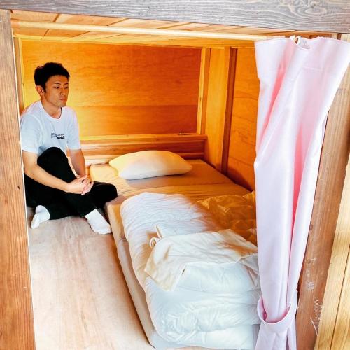 a man sitting on a bed in a room at Challenge kyoten YOKANA - Vacation STAY 63968v in Noma