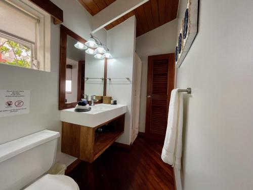 un bagno con lavandino, WC e specchio di Mata Rocks Resort a San Pedro