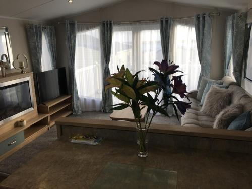 una sala de estar con sofá y un jarrón de flores en 6 Swan View Haven, Littlesea, en Weymouth