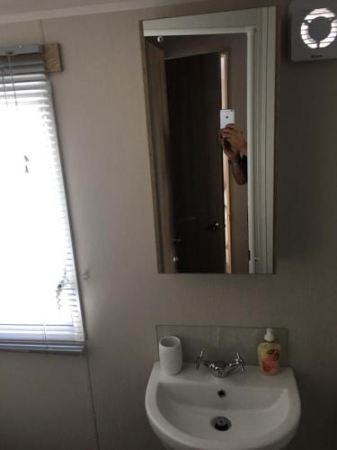 a person taking a picture of a bathroom mirror at Swan View Haven, Littlesea in Weymouth