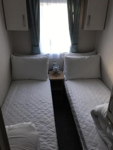 two twin beds in a small room with a window at Swan View Haven, Littlesea in Weymouth