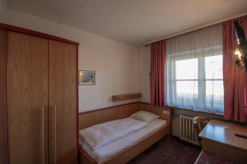 Habitación pequeña con cama y ventana en Hotel Schachtnerhof, en Wörgl