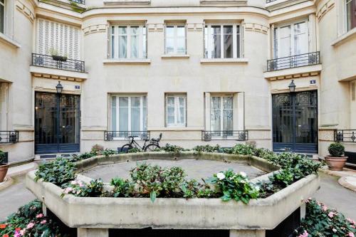 un bâtiment avec un jardin fleuri devant lui dans l'établissement Appartement Carpette - Welkeys, à Paris
