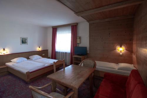 ヴェルグルにあるHotel Schachtnerhofのベッド2台とテーブルが備わるホテルルームです。