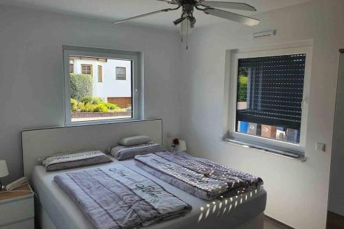 Bett in einem Zimmer mit 2 Fenstern in der Unterkunft Ruhige Wohnung mit Terrasse in Oberbrechen