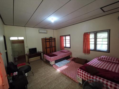 Habitación con 2 camas y mesa. en Happy Resort, en Khanom