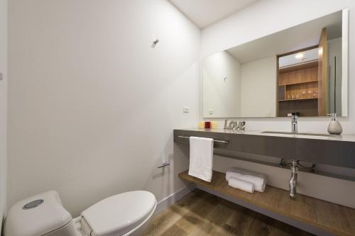 a bathroom with a toilet and a sink and a mirror at Go Living and Suites El Poblado - Jalo Rent in Medellín