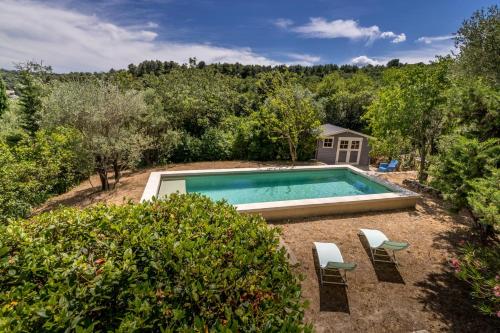- une piscine au milieu d'une cour avec 2 chaises dans l'établissement MAISON AVEC PISCINE - PROCHE AVIGNON - WiFI GRATUIT, à Sauveterre