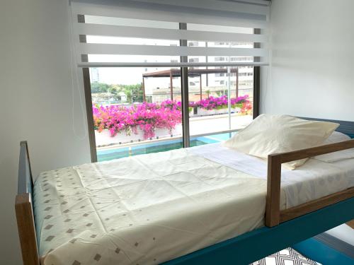 een slaapkamer met een bed en een raam met roze bloemen bij APARTAMENTO Samaria Pozos Colorados 6per 2Hb Santa Marta in Santa Marta