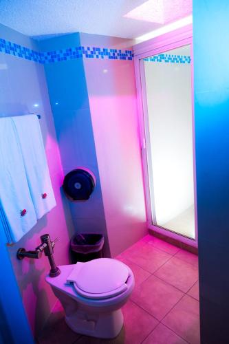 a pink bathroom with a toilet and a shower at Motel California in Jiutepec