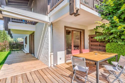 une terrasse en bois avec une table et des chaises dessus dans l'établissement Appartement des Cerisiers - Welkeys, à Megève