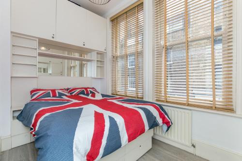 a bedroom with a red white and blue bed and windows at Radio Apartments London - Covent Garden in London