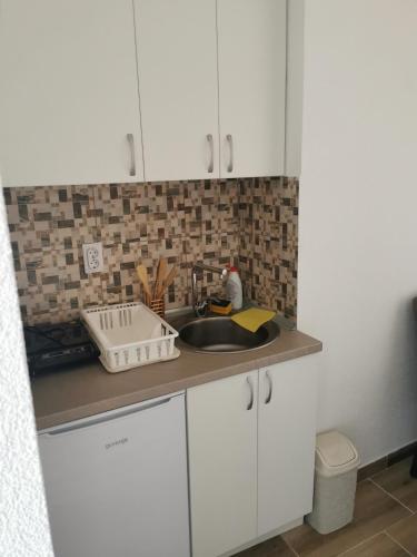 a kitchen with white cabinets and a sink at Apartmani Manila, Vrnjačke terme-popust, SPA centar Pegaz-popust, garažno mesto in Vrnjačka Banja