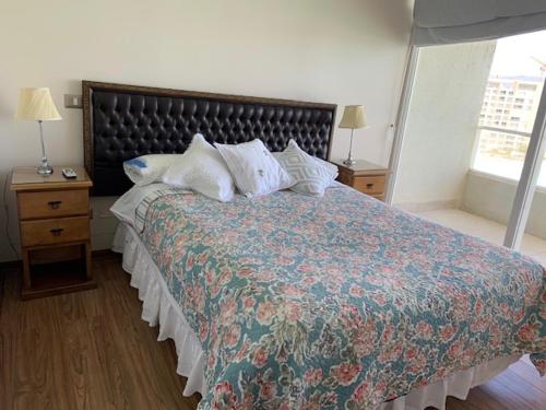 Un dormitorio con una cama grande con almohadas. en Departamentos Laguna del mar, en La Serena