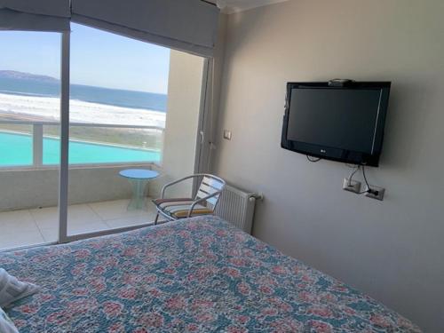 1 dormitorio con 1 cama y TV de pantalla plana en la pared en Departamentos Laguna del mar, en La Serena