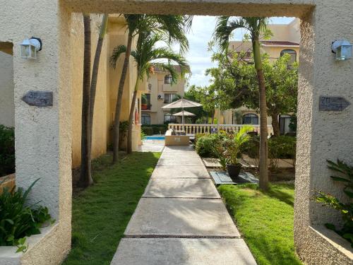 a walkway through the courtyard of a resort with palm trees at Tropical apartment in Cancún