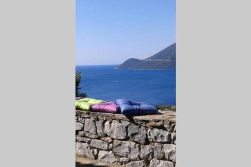 a stack of pillows on a stone wall next to the ocean at Kalivia House - Entire Home in Gythio