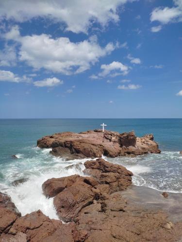a cross on top of some rocks in the ocean at El Belga Loco in Las Peñitas